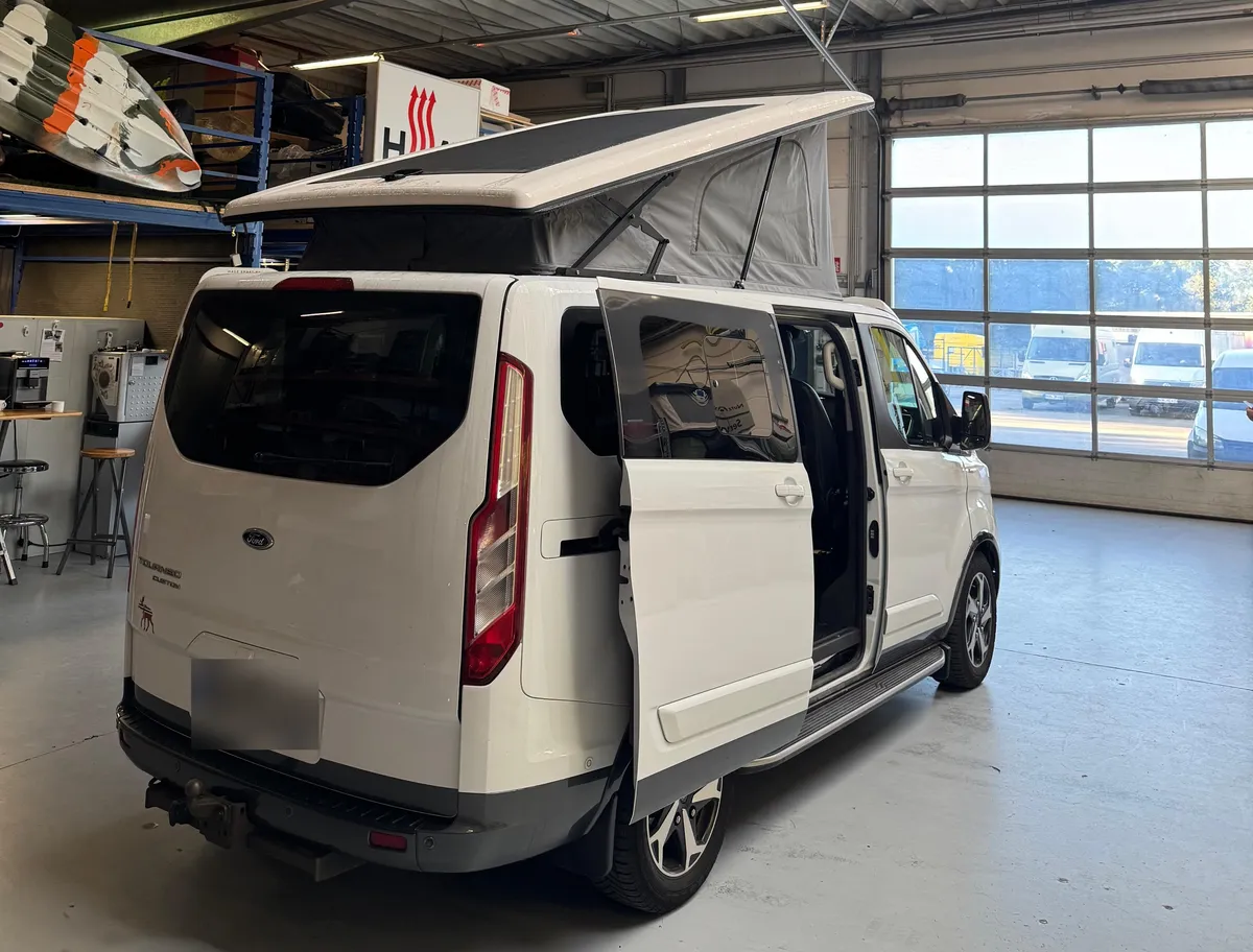 Ford Tourneo Custom von hinten mit geöffnetem Aufstelldach und Solarmodul